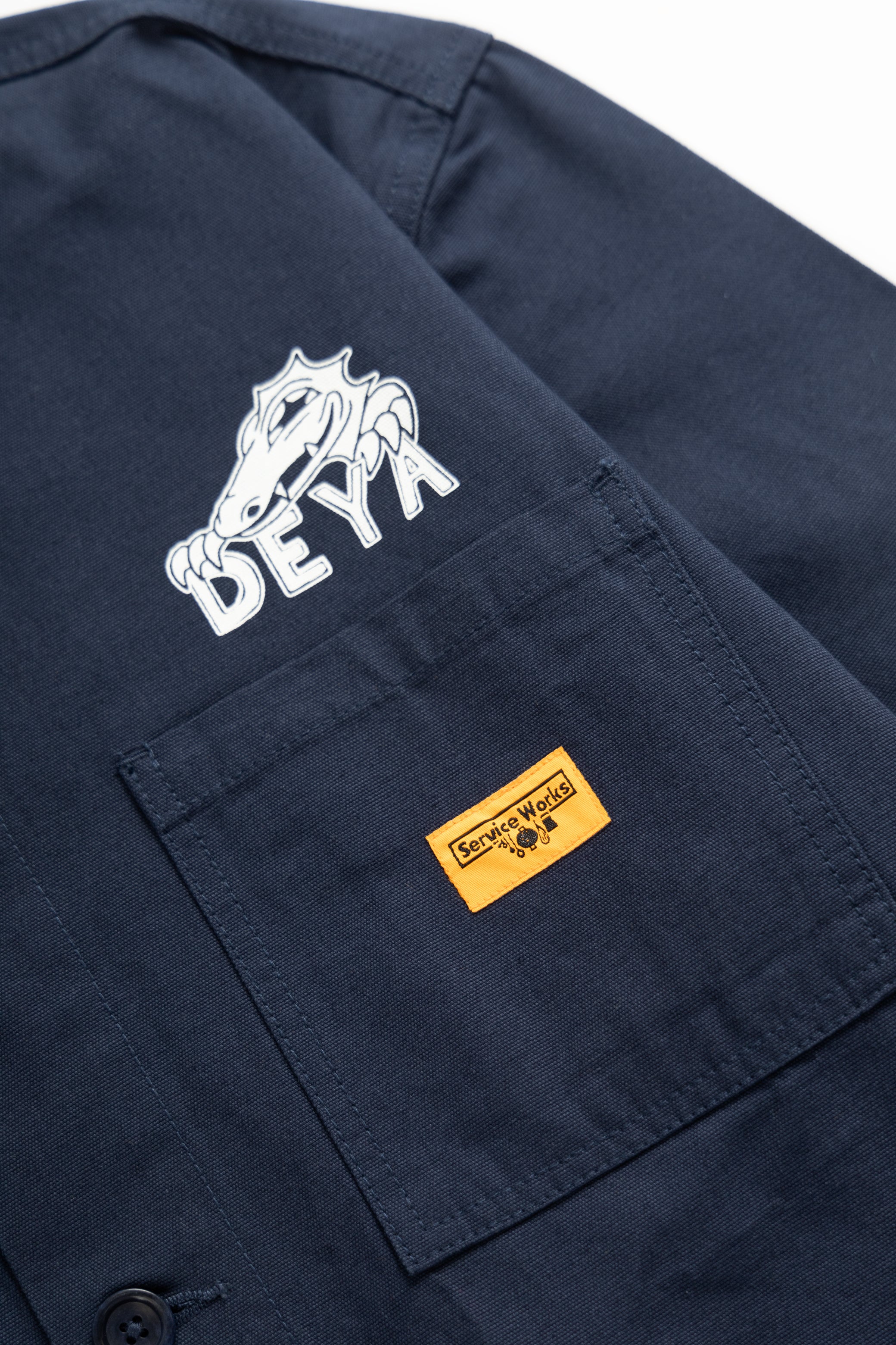 DEYA x Service Works Navy Blue BOH Coverall Jacket - close up DEYA Logo